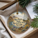 A decorative ornament with a scenic landscape of a lake, mountains, and pine trees, along with a boat and birds, is displayed in a box.