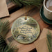 A round ornament with a scenic image of Sadlers Creek State Park, South Carolina, hanging on a wooden surface.