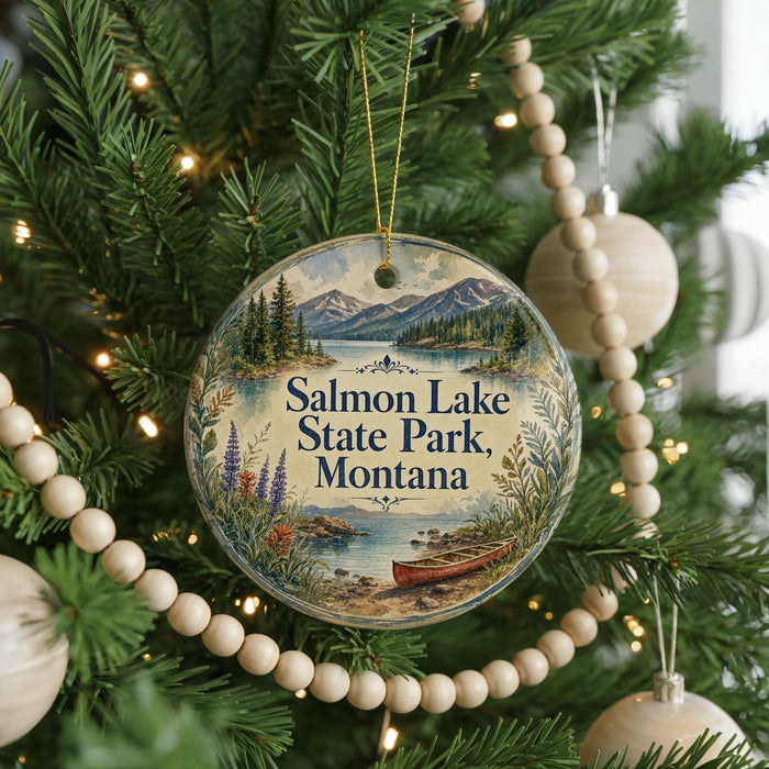 A round ornament hanging on a Christmas tree, featuring a scenic image of Salmon Lake State Park in Montana.