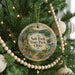 A round ornament hanging on a Christmas tree, featuring a scenic landscape with a lake, trees, and a deer.