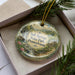 A decorative ornament in a box, featuring a scenic landscape with a house and trees, with the text "Salt Springs State Park, Pennsylvania" prominently displayed.
