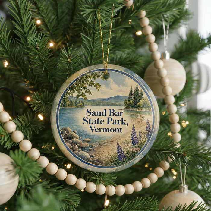 A round ornament hanging on a Christmas tree, featuring a scenic image of Sand Bar State Park in Vermont.