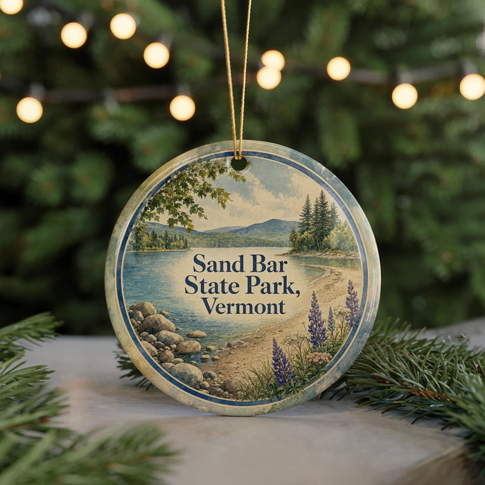 A round ornament with a scenic image of Sand Bar State Park, Vermont, featuring a beach, mountains, and pine trees.
