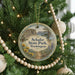 A round ornament hanging on a Christmas tree, featuring a scenic landscape with mountains, trees, and a winding path.