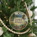 A round ornament hanging on a Christmas tree, featuring a scenic image of Sequest State Park in Washington.