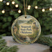 A round ornament with a scenic landscape of Sequoyah State Park, Oklahoma, featuring a waterfall and a castle, is displayed against a blurred background of Christmas lights.