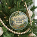 A round ornament hanging on a Christmas tree, featuring an illustration of Shirley Chisholm State Park in New York.