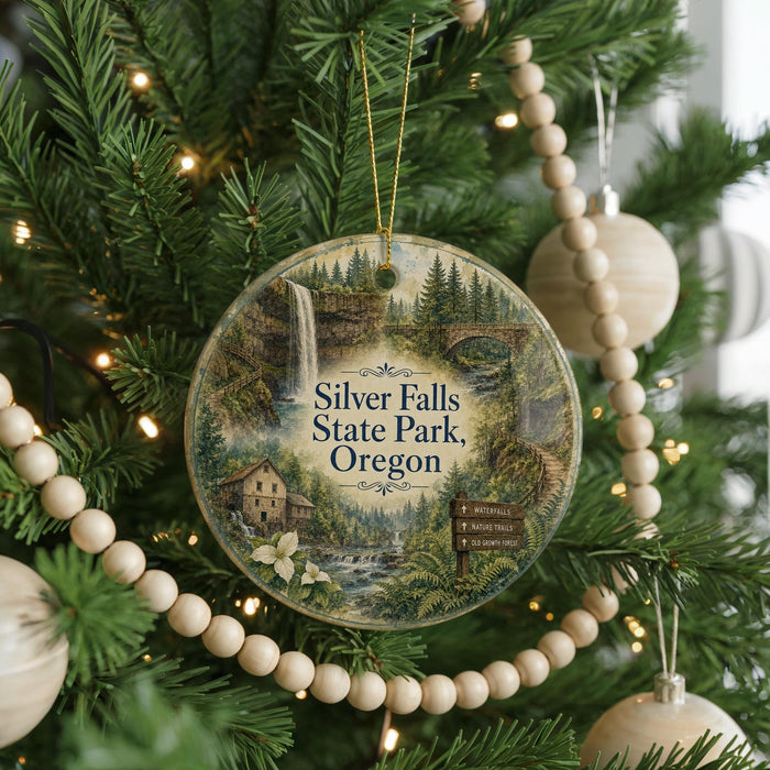 A round ornament hanging on a Christmas tree, featuring a scenic image of Silver Falls State Park, Oregon.
