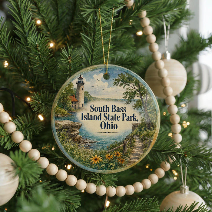 A round ornament hanging on a Christmas tree, featuring a lighthouse and a scenic landscape.