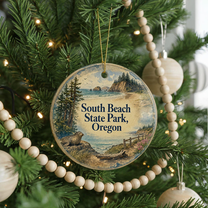A round ornament hanging on a Christmas tree, featuring a scenic landscape with a beach, mountains, and a moose.
