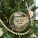 A round ornament hanging on a Christmas tree, featuring a scenic landscape with a beach, mountains, and a moose.