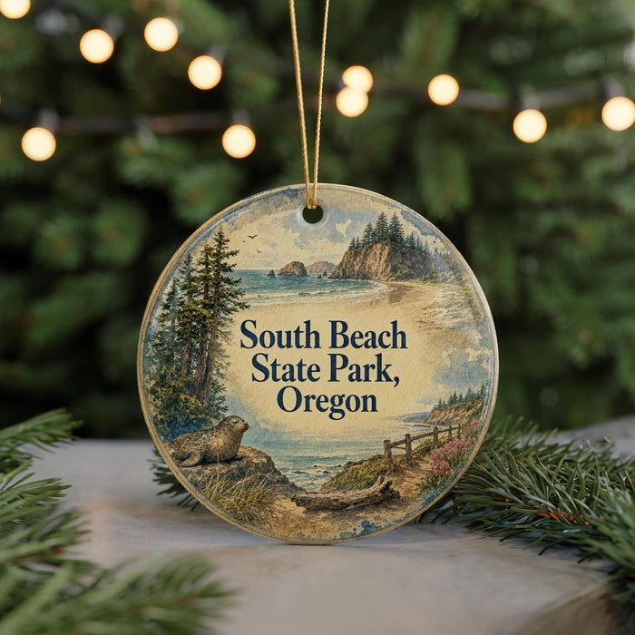 A round ornament with a scenic landscape of South Beach State Park, Oregon, featuring a bear, pine trees, and a body of water.