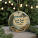 A round ornament with a scenic landscape of South Beach State Park, Oregon, featuring a bear, pine trees, and a body of water.
