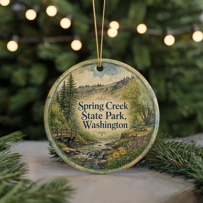 A round ornament with a scenic image of Spring Creek State Park, Washington, featuring a bridge, trees, and a stream.