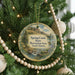 A round ornament hanging on a Christmas tree, featuring a scenic landscape of a river and mountains.