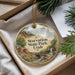 A round ornament with a scenic landscape of mountains, trees, and a waterfall, hanging from a string.