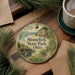 A round ornament with a scenic image of Stonelick State Park, Ohio, is displayed on a wooden surface alongside a cup of coffee and some pine branches.