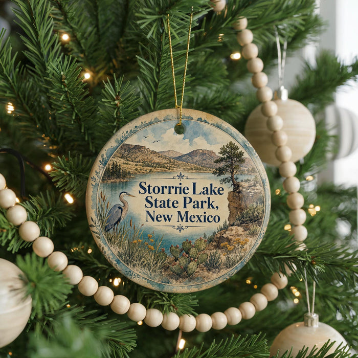 A round ornament hanging on a Christmas tree, featuring a scenic landscape with mountains, a lake, and a bird.