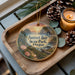 A decorative ornament featuring a scenic landscape of Sunset Bay State Park, Oregon, with pine cones and a lit candle on a wooden tray.