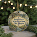A round ornament with a scenic landscape and text, hanging on a string.