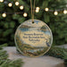 A circular ornament with a scenic landscape of a lake, mountains, and a bird, hanging from a string.