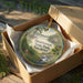 A decorative ornament in a wooden box, featuring a scenic landscape with a river, trees, and a house, with the text "Swartswood State Park, New Jersey" printed on it.