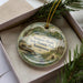 A decorative ornament in a box, featuring a scenic image of Sycamore Shoals State Historic Park in Tennessee.