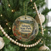 A circular ornament hanging on a Christmas tree, featuring a scenic image of Talimanena State Park in Oklahoma.