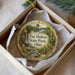 A decorative ornament in a box, featuring a scenic landscape with a waterfall and forest.