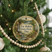 A round ornament hanging on a Christmas tree, featuring a scenic landscape with a waterfall and a path leading to a cliff.