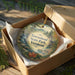 A decorative ornament in a box, featuring a scenic landscape with a waterfall and pine trees, with the text "Townshend State Park, Vermont" printed on it.