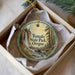 A round ornament with a scenic image of a waterfall and forest, hanging from a string inside a box.
