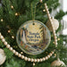 A round ornament hanging on a Christmas tree, featuring a scenic image of a waterfall surrounded by pine trees and a bridge.