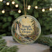 A circular ornament with a painting of a waterfall and forest, hanging on a string.