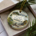 A decorative ornament with a scenic landscape of Twanoh State Park, Washington, featuring pine trees, mountains, and a body of water.