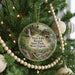 A round ornament hanging on a Christmas tree, featuring a scenic image of Twin Falls Resort State Park, West Virginia.