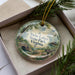 A decorative ornament in a box, featuring a scenic landscape with a bridge and trees, with the text "Twin Lakes State Park, Virginia" prominently displayed.