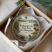 A decorative ornament in a box, featuring a moose, a canoe, and a scenic landscape with a lake and mountains.