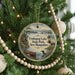 A round ornament hanging on a Christmas tree, featuring a scenic image of Umbog Lake, State Park, and New Hampshire.