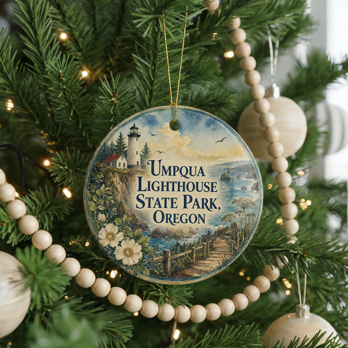 A round ornament hanging on a Christmas tree, featuring a lighthouse and a scenic landscape.