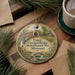 A decorative ornament featuring a bridge and a house, with the text "Union Covered Bridge State Historic Site, Missouri" printed on it. The ornament is placed on a wooden surface, surrounded by pine branches and a cup of coffee.