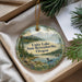 A decorative ornament with a scenic landscape featuring a lake, mountains, pine trees, and a bird, hanging from a string.