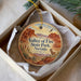 A decorative ornament in a box, featuring a desert landscape with mountains and a bird in flight.