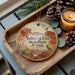 A wooden tray with a decorative ornament featuring a scenic landscape of Valley of Fire State Park, Nevada, along with pine cones and a lit candle.