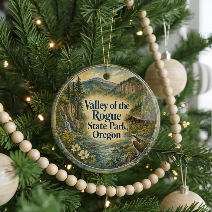 A round ornament hanging on a Christmas tree, featuring a scenic image of the valley of the Rogue State Park, Oregon.