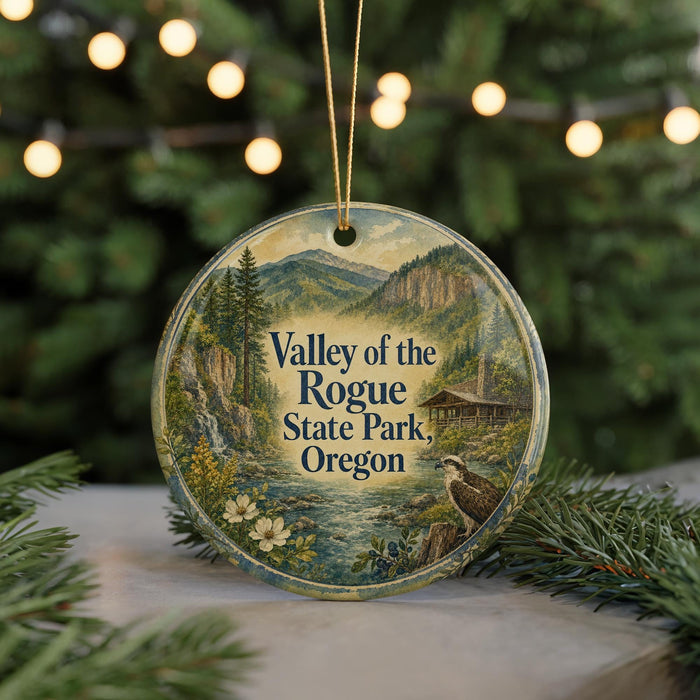 A round ornament with a scenic landscape of mountains, trees, and a river, featuring a bird perched on a rock.