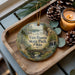 A decorative ornament featuring a scenic image of Van Buren State Park, Ohio, with pine cones and a lit candle on a wooden tray.