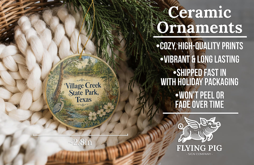 Ceramic ornaments, including a round ornament with a scenic design, are displayed in a basket with greenery.