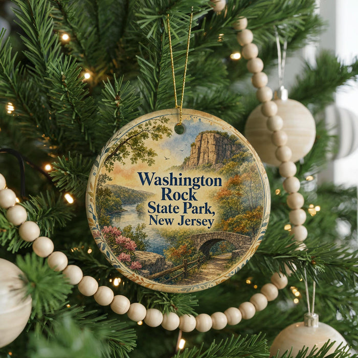 A round ornament hanging on a Christmas tree, featuring a scenic landscape with a bridge and mountains in the background.