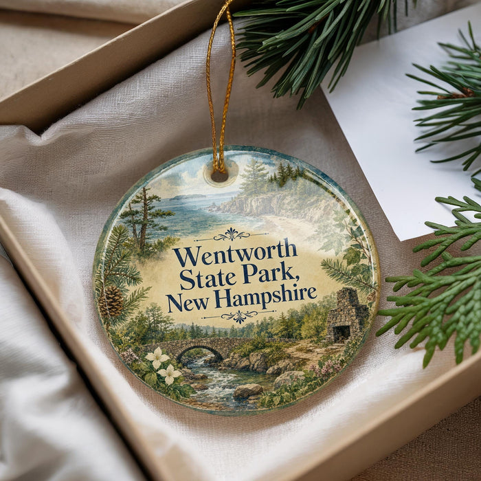 A decorative ornament with a scenic landscape of Wentworth State Park, New Hampshire, featuring a bridge, pine trees, and a body of water.